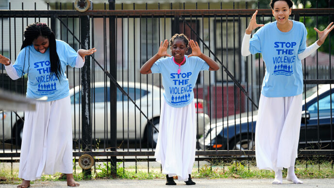 Three young dancers perform outside wearing t-shirts that say Stop The Violence